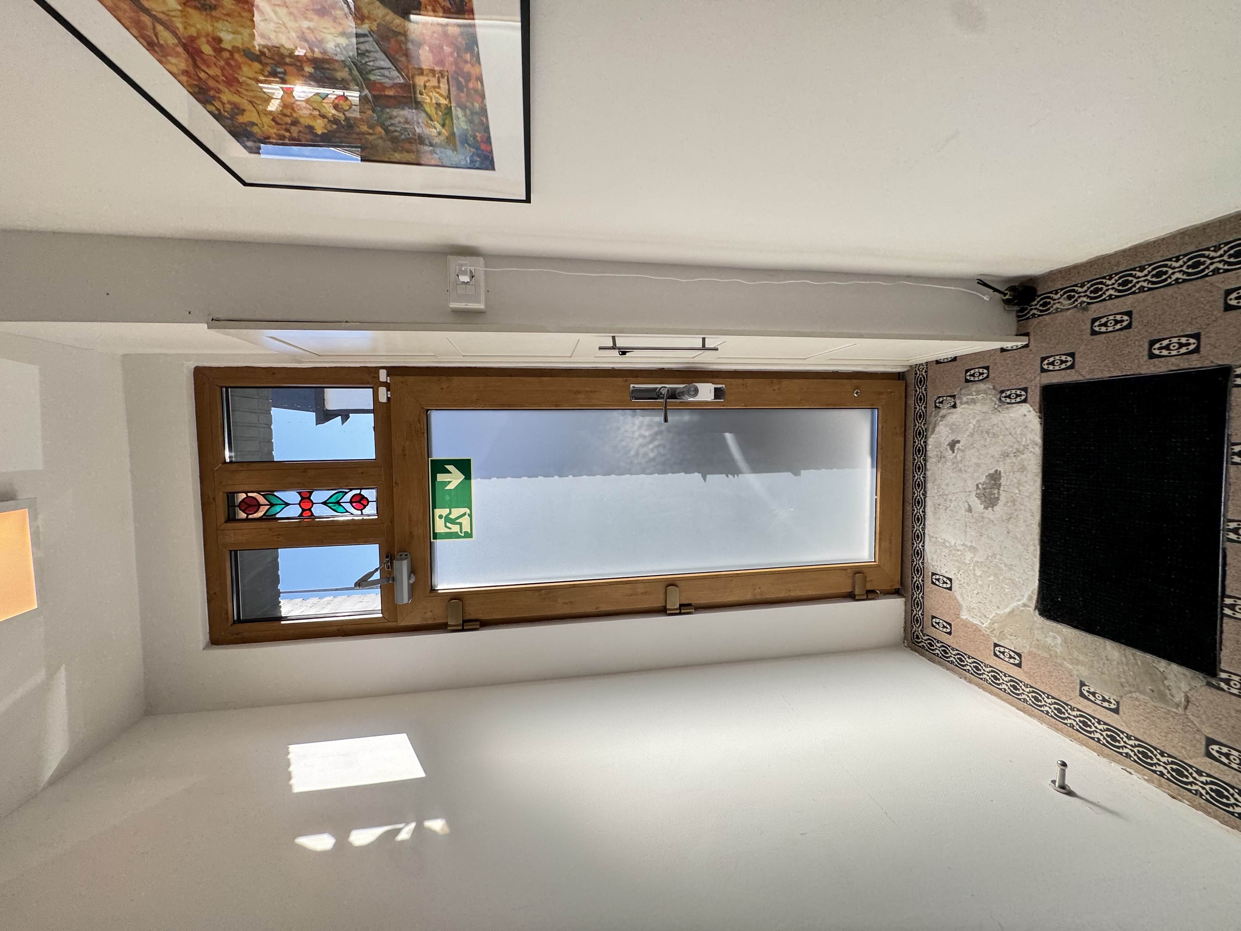 Main building door from inside, glazed top panel with green Exit pictogram.