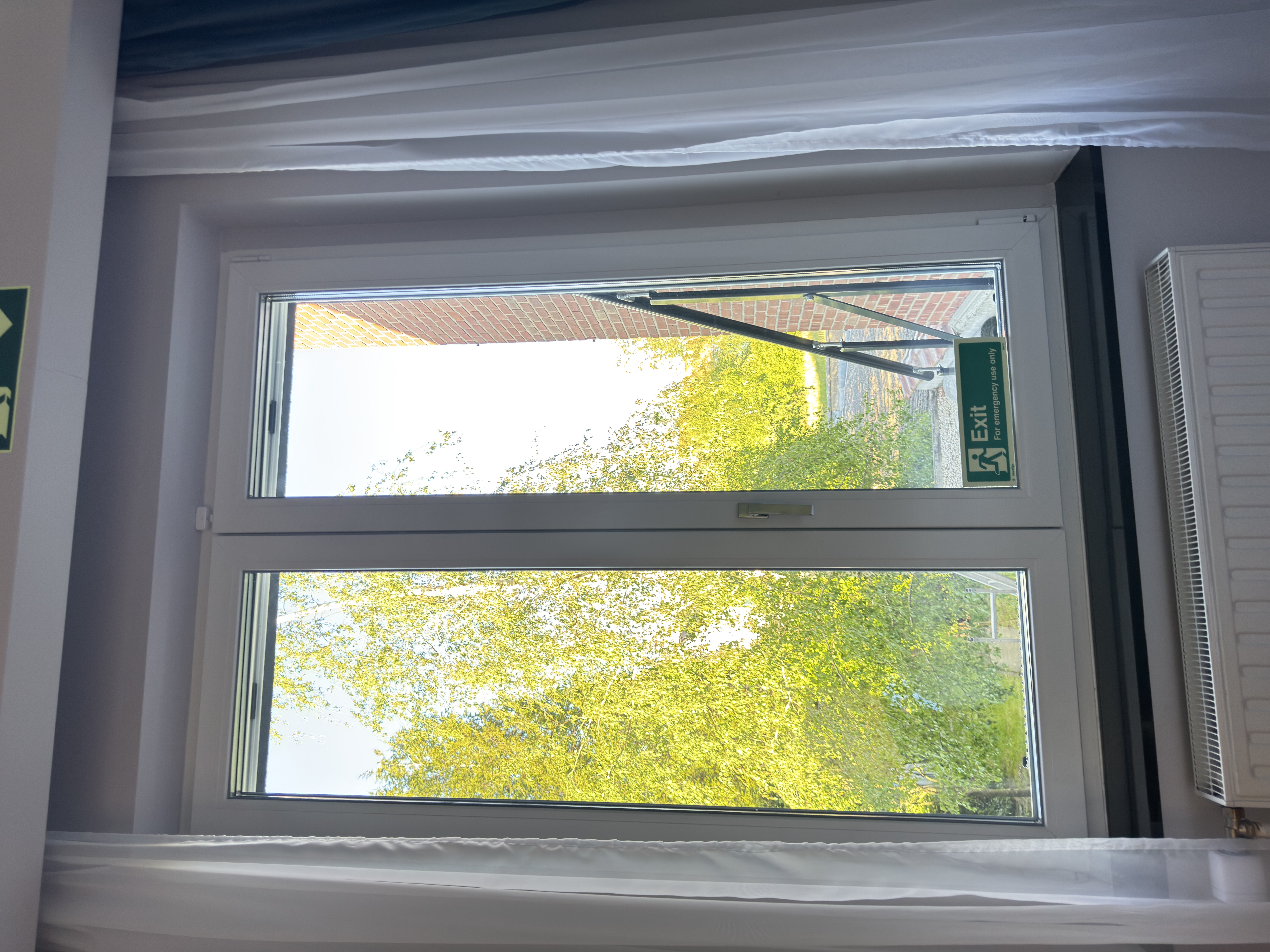 Bedroom showing the green Exit pictograms pointing to the emergency window.